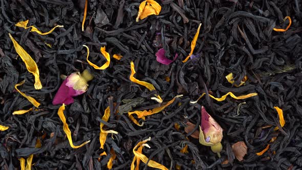 Dry herbs tea with fruit and flower petals as background, top view, rotates