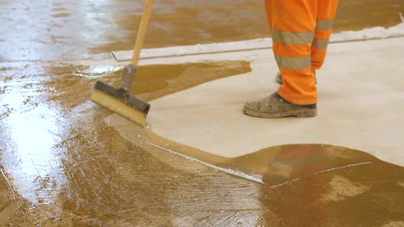 A Worker in Overalls Rubs the Spilled Primer with a Spatula