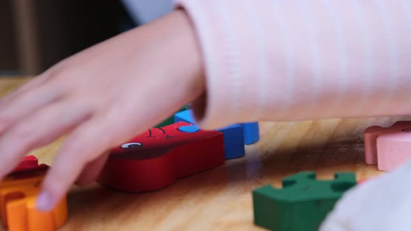 Cute young girl wearing pajamas playing wooden puzzles jigsaw at home. alt