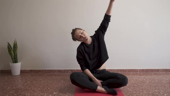 Altrenativa woman doing stretching at home sitting on the floor and with decorative plants