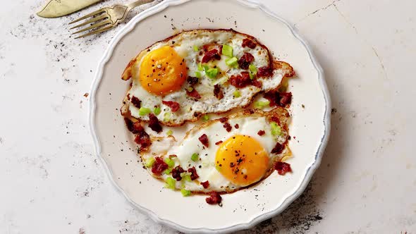 Two Fresh Fried Eggs with Crunchy Crisp Bacon and Chive Served on Rustic Plate