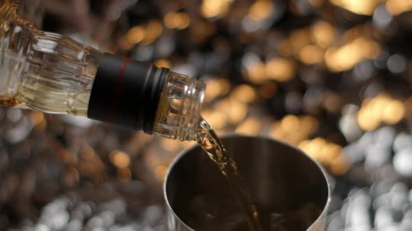 Whiskey is Being Poured in Slow Motion to the Cocktail Shaker with Ice Making the Alcohol Drink