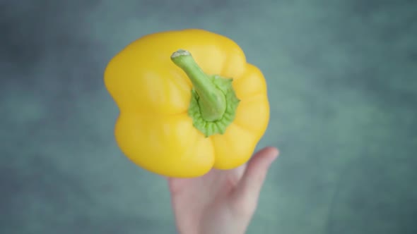 Person Throws Up Uncooked Yellow Bellpepper Above Table