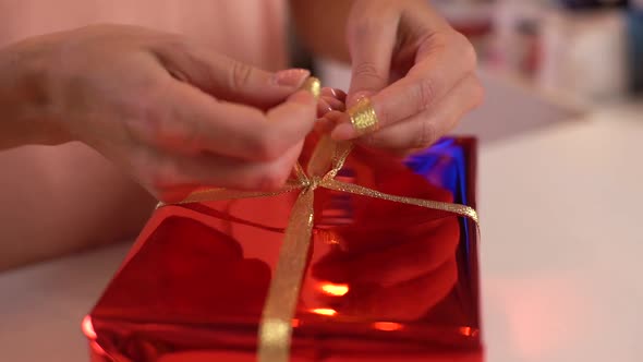 Closeup Highangle View Hands of Unrecognizable Young Woman Wrapping Red Christmas Gift Box Tying