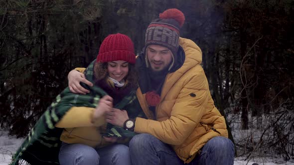 Guy Shelters a Girl with a Blanket in the Woods in Winter