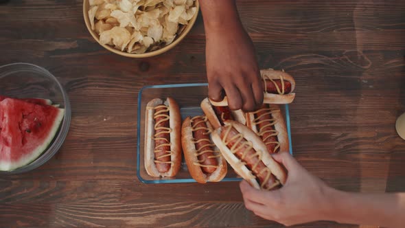 Hands Taking Hot Dogs