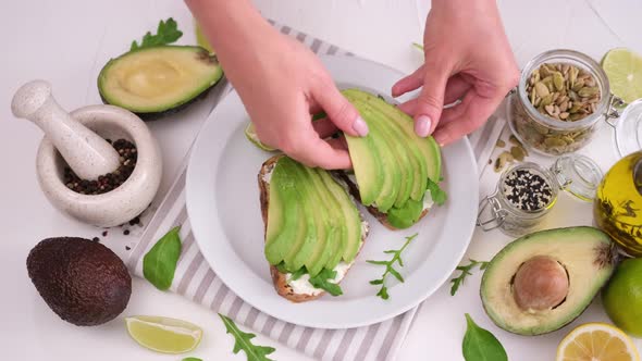 Woman Prepares a Healthy Breakfast or Snack  Soft Cheese Sandwich with Avocado