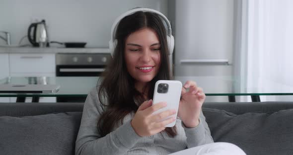 A Lovely Smiling Millennial Teen Girl is Talking to Someone with a Video Chat While Sitting in the