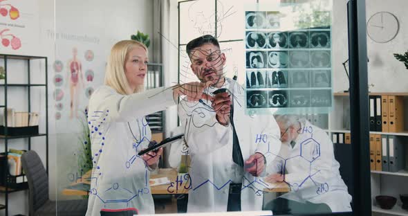 Male and Female Doctors Working Together in Medical Lab with Patient's X-ray Scan