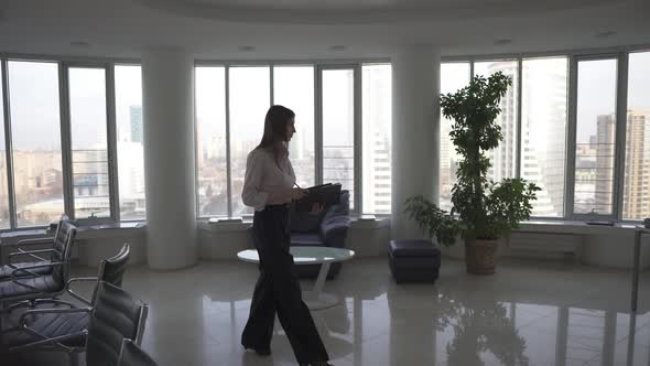 Business Woman Viewing Documents Walking Through a Spacious Office