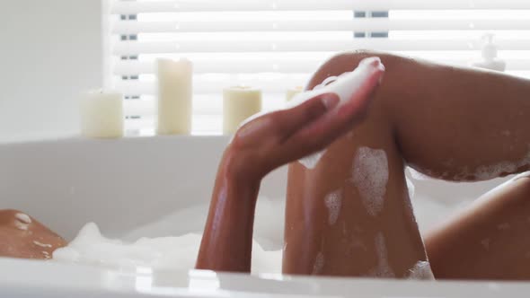 Close up of african american woman blowing soap bubbles in the bath tub in the bathroom at home