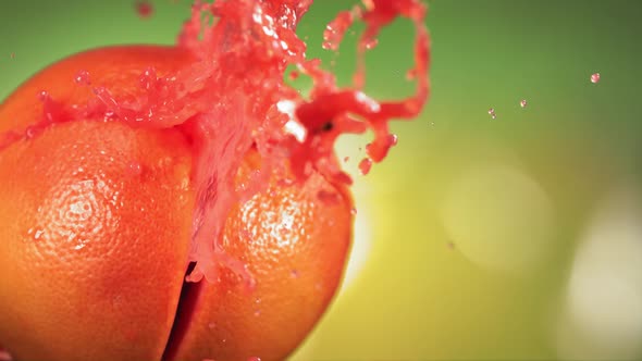 Fresh Grapefruit Fruit Squirting with Juice in Slow Motion in Green Nature Background