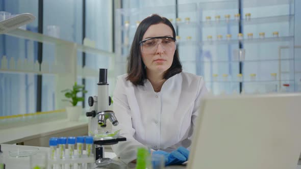 Dissatisfied and Puzzled a Female Scientist Looks Through a Microscope in a Modern Laboratory