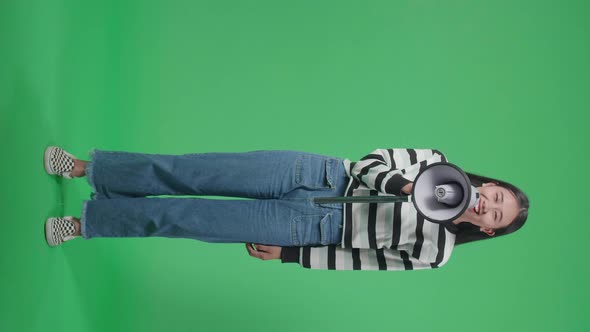 Full Body Of A Smiling Asian Woman Speaking On Megaphone In The Green Screen Studio