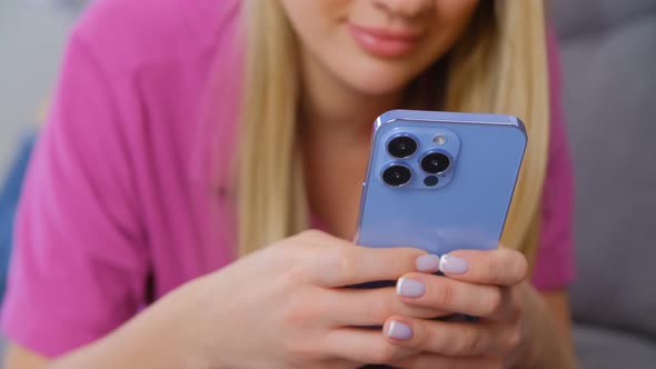 Young adult blonde girl using modern smartphone with triple camera for communication in 4k video
