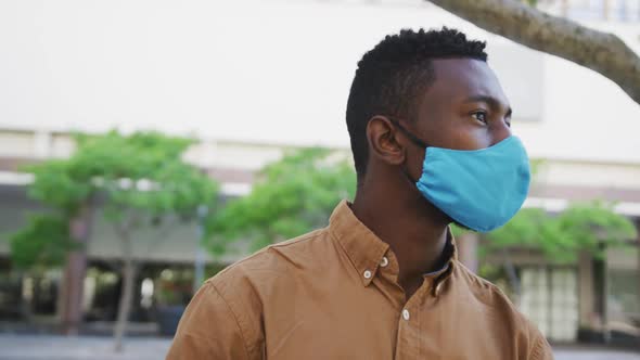 African american businessman wearing face mask sitting in park