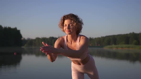 Slim athletic woman is engaged in yoga. Morning yoga classes on the beach at sunrise.