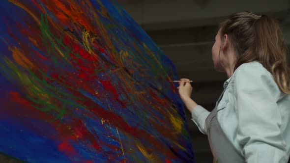 Artist in an Apron Paints a Picture on Canvas with Oil Paints in His Studio