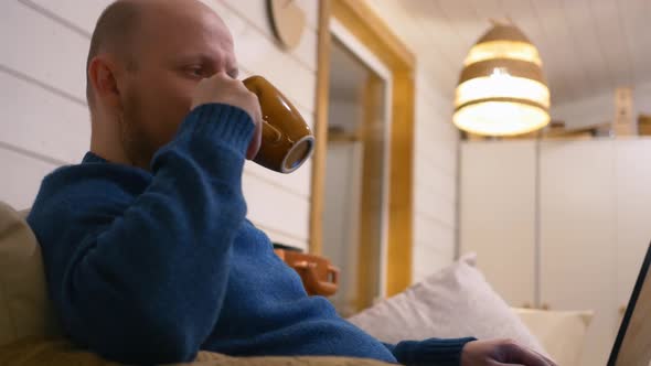 A Middleaged Man Drinks Coffee at Home While Working at a Computer