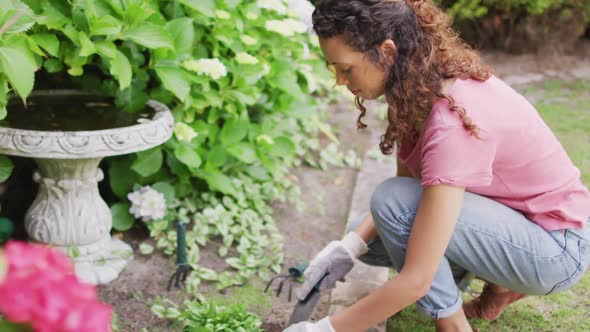 Side view of biracial woman gardening, planting flowers