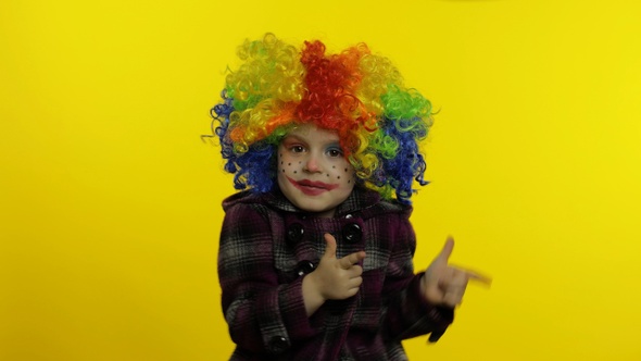 Little Child Girl Clown in Colorful Wig Making Silly Faces, Having Fun, Smiling, Dancing. Halloween