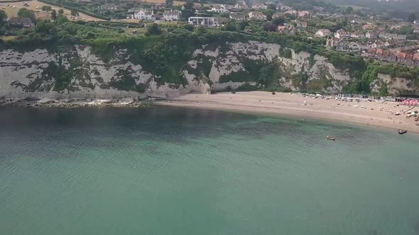 Aerial view showing the beautiful village of Beer in Devon, UK. Descending down towards the ocean.