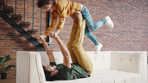 Father and Stepson Perform Acrobatic Stunt on Sofa at Home