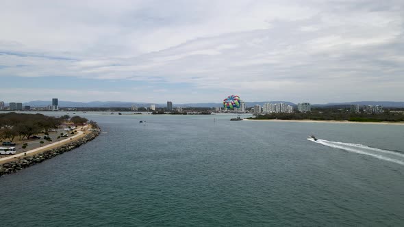 Aerial view of a fast boat pulling a parasail through the air with a city skyline in the background