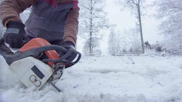 CHAINSAW CU - a woman cuts an ice hole for cold water exposure therapy
