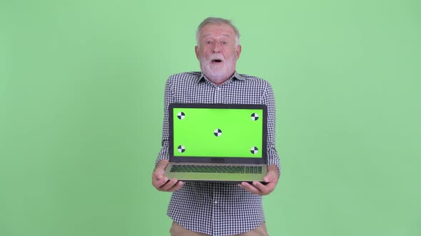 Happy Senior Bearded Man Showing Laptop and Looking Surprised