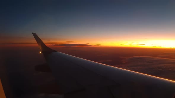 Beautiful orange sunset view from left airplane wing, turning right