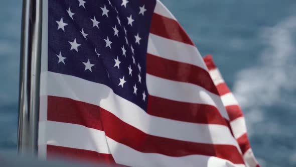 U.S. Flag Evolves in the Wind Against Water in Slow Motion on the Yacht