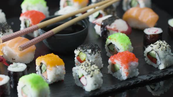 Stone Plate with Sushi and Maki with Sushi Sticks and Soy Sauce.