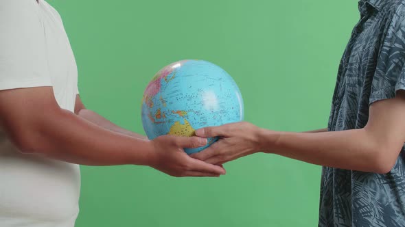 Man Hand In The World Globe To Another Man While Standing In Front Of Green Screen Background