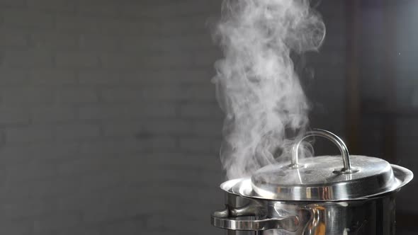 Steam or Vapour Clouds Rising From Boiling Water in Saucepan on Stove