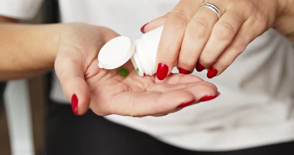 Woman holding pills green chlorophyll on hand pouring two organic vitamins from meds bottle