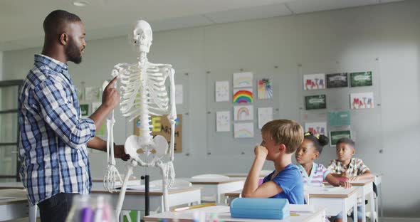 Video of happy african american teacher with class of diverse pupils during anatomy lesson