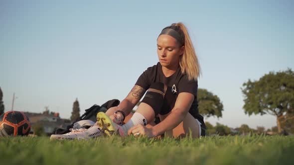 Professional female soccer player lacing up her boots