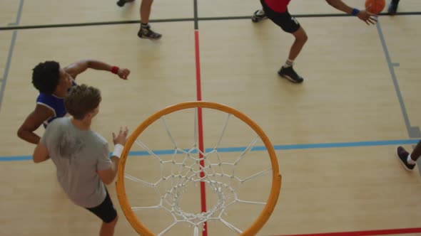 Overhead view of african american male basketball player scoring goal against diverse players