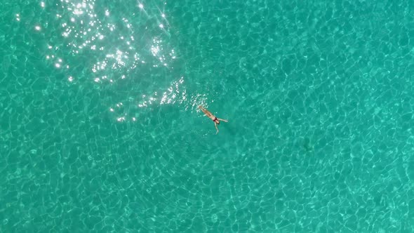 Aerial view of a woman floating in the sea of Ithaca island.