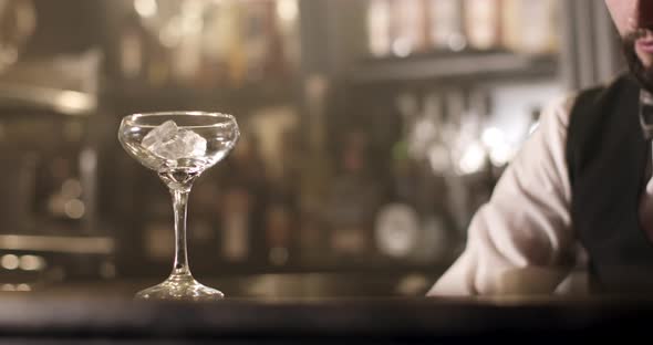 Close-up Shooting. The Bartender Is Filling a Glass with Ice