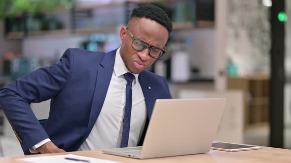 Tired African Businessman with Laptop Having Back Pain in Office 