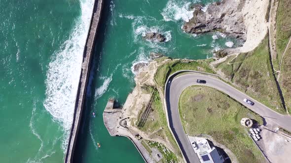 Cars Driving In Lighthouse Hill By Curve Road With Ocean Waves On Pier Near Village Of Portreath, Co