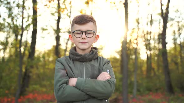Portrait of a Boy with Glasses on a Forest Background at Sunset