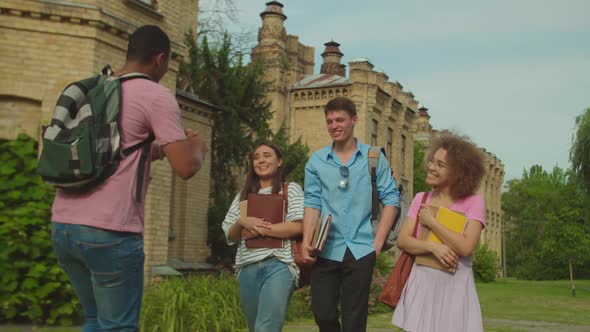 Young Man Going Backwards Telling Stories to Diverse Friends Outdoors