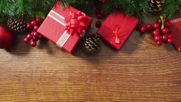 Video of christmas decorations with presents and copy space on wooden background