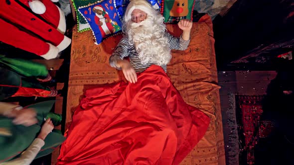 Santa Claus is sleeping in specially decorated room in his bed. 