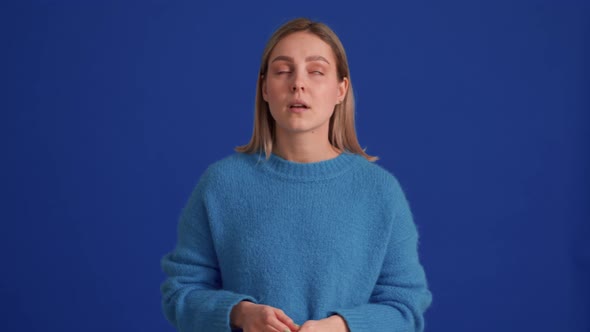 Dissatisfied woman wearing blue sweater clapping hands