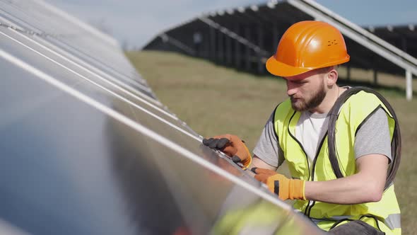 Male Engineer in a Uniform Is Checking the Solar Battery Outside