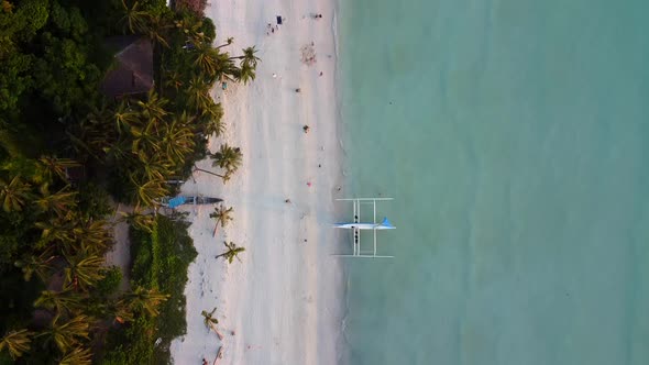 A Sandy Tropical Beach With Crystal Blue Water, Green Palm Trees and Boats On The Shore